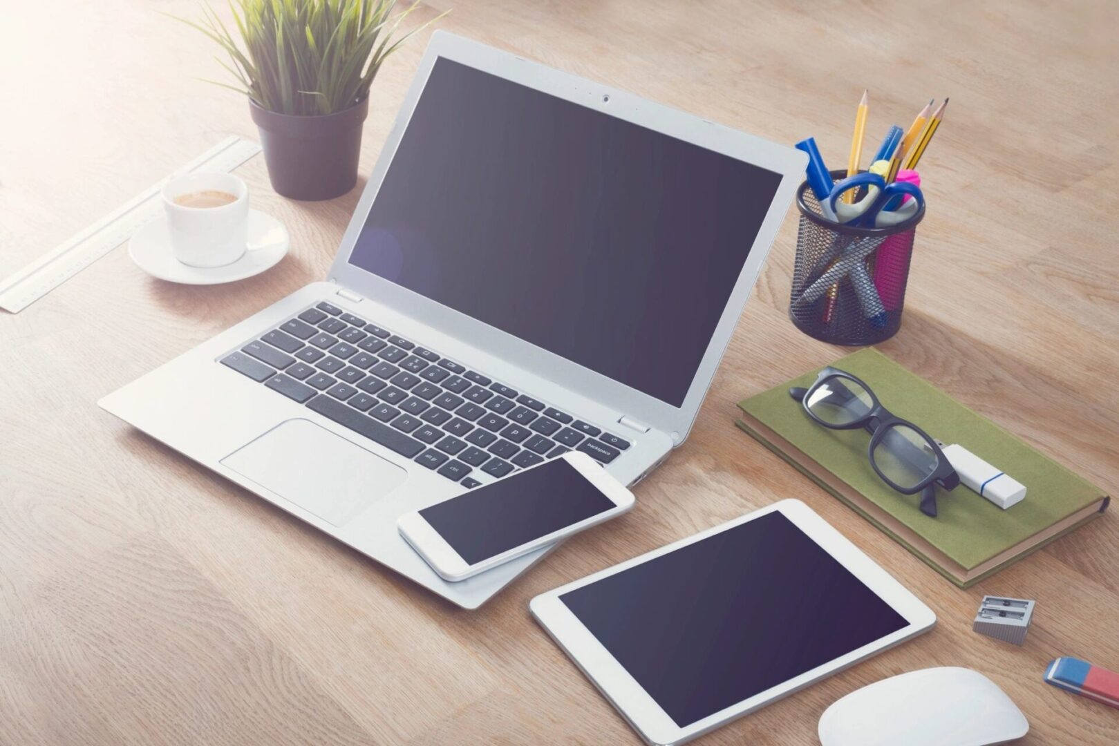 A laptop, tablet and phone on a table.